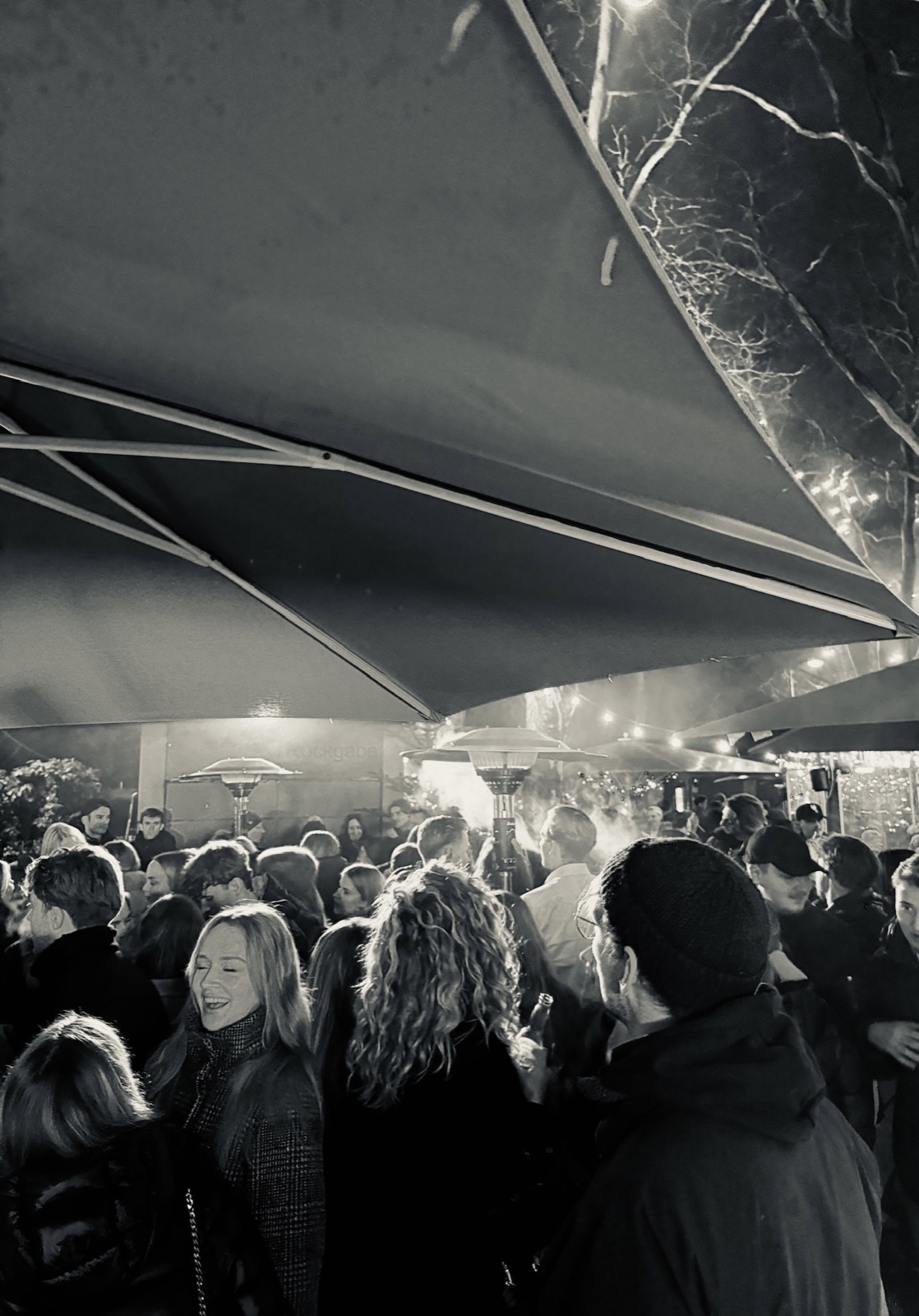 Gäste einer SOL Party im Außenbereich unter Sonnenschirmen und Heizstrahlern